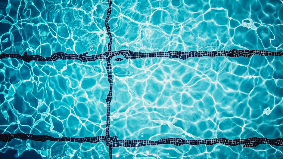Close-up of a shimmering turquoise swimming pool surface with tile lines.